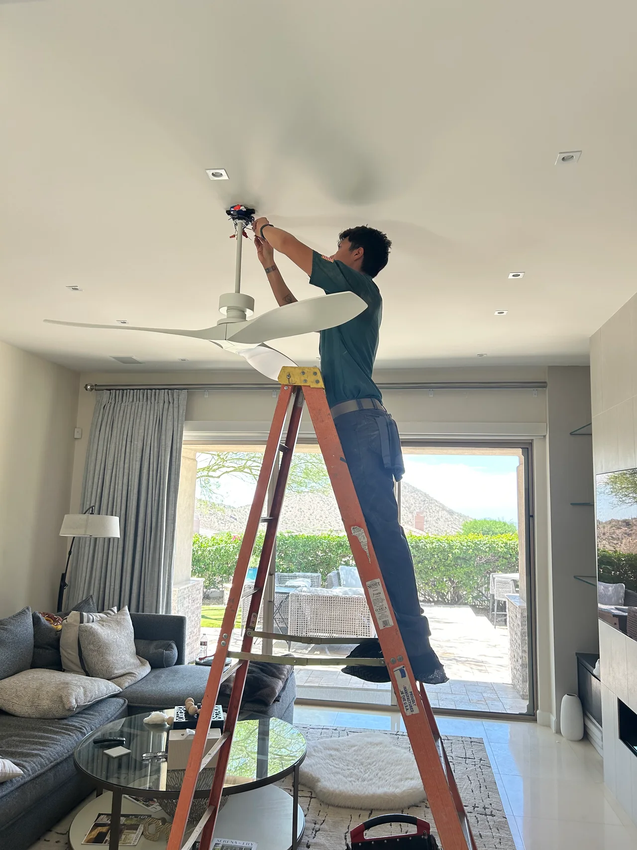 Electrician installing the ceiling fan at Gina’s home